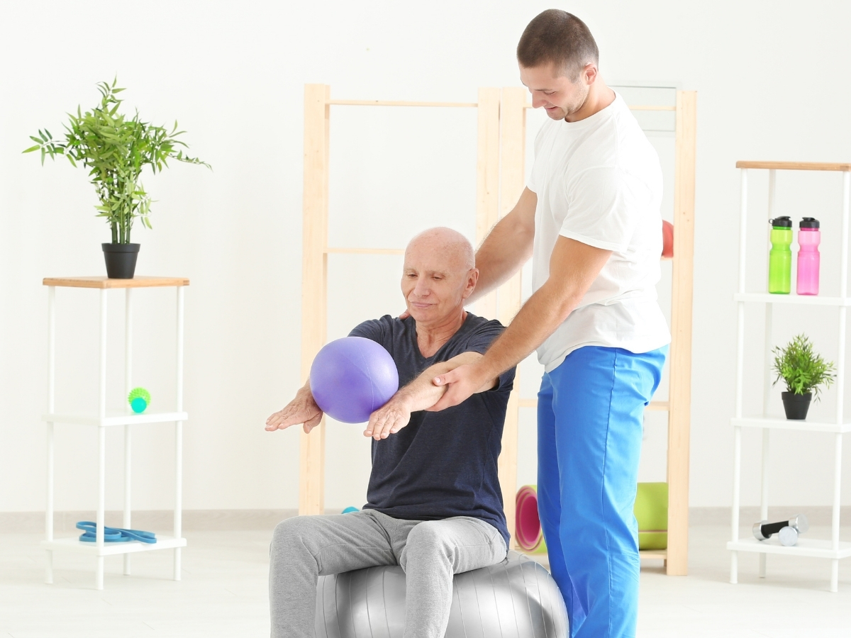 Male physical therapist working on upper body exercises with an elderly gentleman