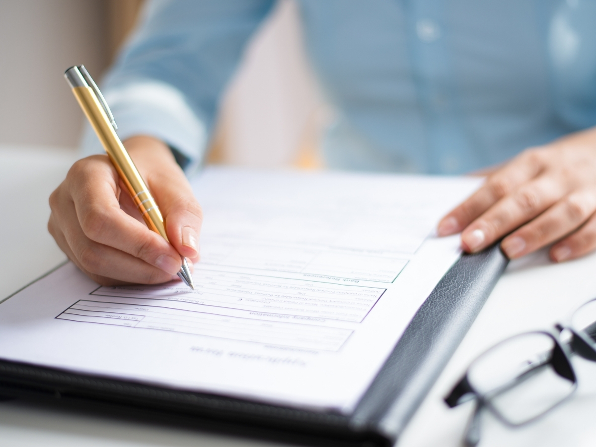 Close-up of a professionally attired woman filling out paperwork