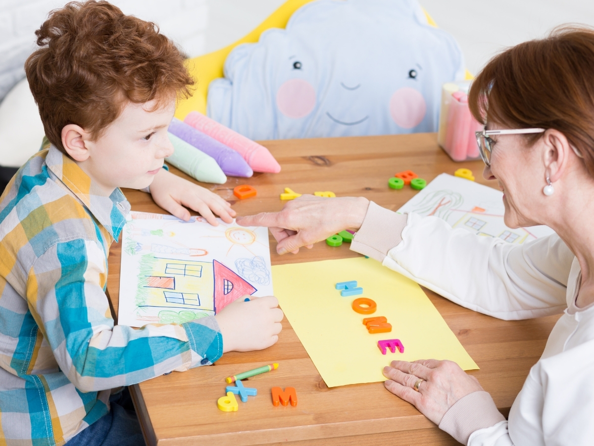 Female pediatric therapist working on letters and drawing with a young boy