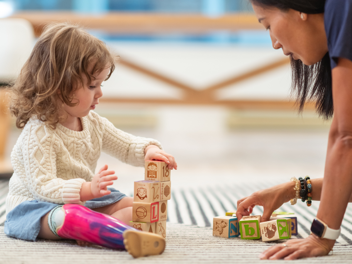 Pediatric occupational therapist playing blocks with female toddler